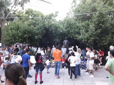 a large crowd of people standing around a statue at Alexandra's path in Athens