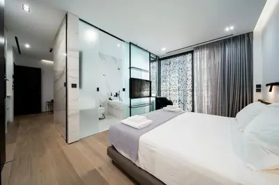 a bedroom with a large white bed and a bathroom at The Duke Boutique Suites in Athens