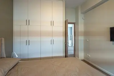 a bedroom with a bed with white cabinets and a tv at THE apartment 2 BDRS/2 BATHS luxury residence in Athens