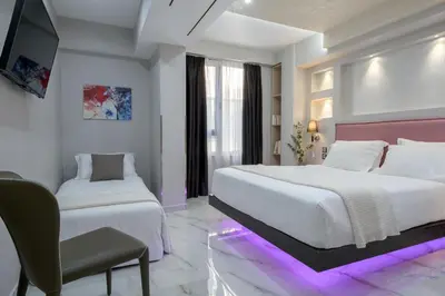 a white bedroom with two beds and a chair at Athens Starlight Hotel in Athens