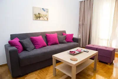 a living room with a gray couch with pink pillows at Acropolis,Historic center Apartment-update in Athens