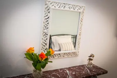 a mirror and a vase with flowers on a table at Acropolis,Historic center Apartment-update in Athens