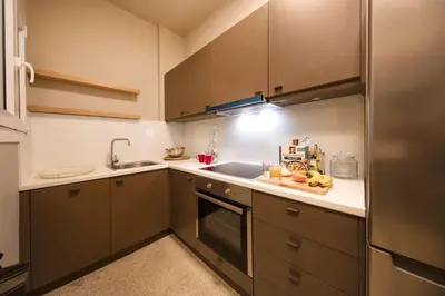 a small kitchen with brown cabinets and a sink at Brand new Modern Apartment with satellite TV in Athens