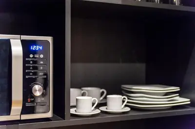 a microwave oven with cups and plates on a shelf at 33SolonosSuites in Athens