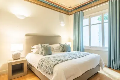 a bedroom with a bed with blue curtains and a window at 33SolonosSuites in Athens