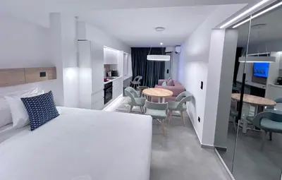 a bedroom with a white bed and a table and chairs at PINACOTA SUITES ATHENS in Athens