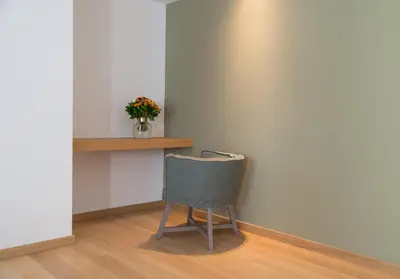 a chair sitting next to a wall with a vase of flowers at PINACOTA SUITES ATHENS in Athens