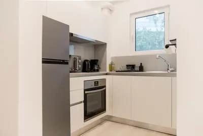 a kitchen with white cabinets and a refrigerator at PINACOTA SUITES ATHENS in Athens