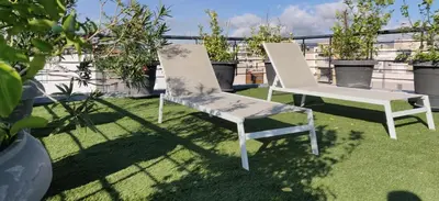 two white chairs sitting on the grass on a balcony at Elegant Bright Apartment with Acropolis view terrace in Athens