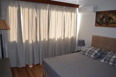 a bedroom with a bed and a window with curtains at METROPOLITAN MACVIEW Διαμέρισμα in Piraeus