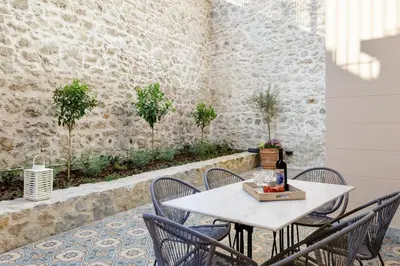 a white table with chairs and a bottle of wine at The Gem of Filopappou in Athens