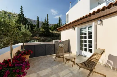 a patio with two chairs and flowers at The Gem of Filopappou in Athens