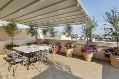 a patio with a table and chairs and potted plants at The Gem of Filopappou in Athens