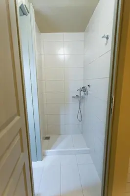a white bathroom with a shower with a sink at Plaka360 Apartments in Athens