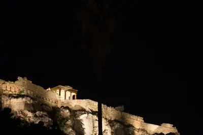 a building on top of a mountain at night at Plaka360 Apartments in Athens
