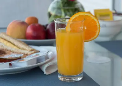 a glass of orange juice next to a plate of fruit at Elegance in Athens in Athens