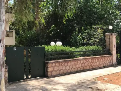 a green gate with a stone wall and a hedge at aris sweet home 2 in Athens
