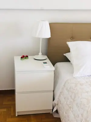 a white nightstand with a lamp on it next to a bed at aris sweet home 2 in Athens