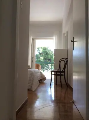 a hallway with a chair and a bed and a cross at aris sweet home 2 in Athens