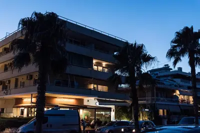 a building with palm trees in front of it at Alex's place in Vari