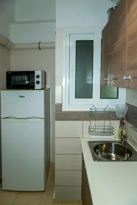 a kitchen with a white refrigerator and a sink at AthensHub - Across Metro Station in Athens