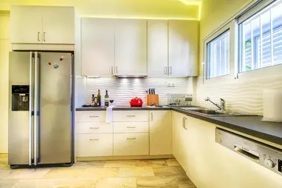 a kitchen with white cabinets and a stainless steel refrigerator at Summer Villa in Porto Rafti in Porto Rafti