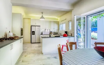 a kitchen with white cabinets and a table with chairs at Summer Villa in Porto Rafti in Porto Rafti
