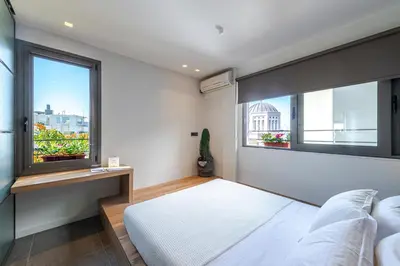 a bedroom with a white bed and two windows at Hidesign Athens Acropolis Panorama Suite in Athens