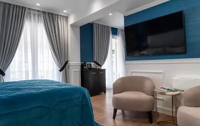 a bedroom with a bed and a tv and a chair at Evripidou Suites in Athens
