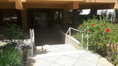 a stairway leading to a building with red flowers at Alianthos Beach Apartment in Vari