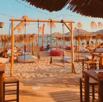 a beach with a bunch of chairs and umbrellas at Alianthos Beach Apartment in Vari