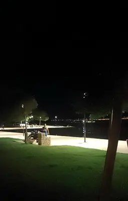 a man sitting on a bench in a park at night at Alianthos Beach Apartment in Vari