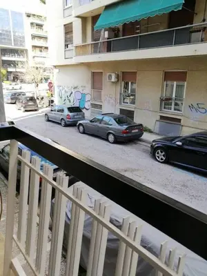 two cars parked on a street in front of a building at Classy and stylish apartment next to Hilton in Athens