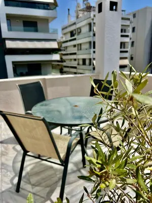 a glass table and chairs sitting on a balcony at Brand new brilliant apartment at Athenian Riviera in Athens