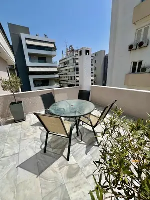 a patio with a table and chairs on a balcony at Brand new brilliant apartment at Athenian Riviera in Athens