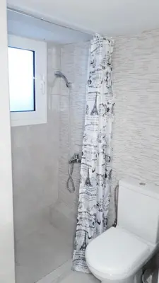 a bathroom with a shower with a toilet and a shower curtain at Stylish apartment near Katechaki in Athens