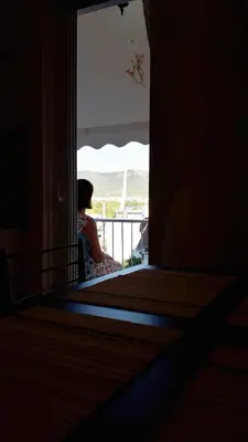 a woman sitting on a balcony looking out of a door at Stylish apartment near Katechaki in Athens