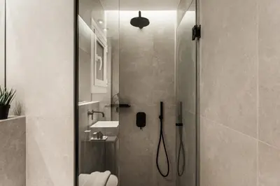 a bathroom with a shower with a toilet and a sink at Modern Minimalist 3BD Apartment in Hilton District by UPSTREET in Athens