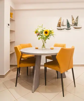 a dining room table with yellow chairs and a vase of flowers at Home pleasure project in Athens