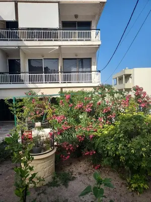 a building with a bunch of flowers in front of it at agia marina riviera aigina in Agia Marina Aegina