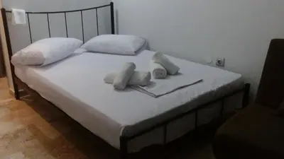 a bed with white sheets and pillows on it at agia marina riviera aigina in Agia Marina Aegina
