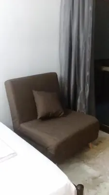 a brown couch sitting in front of a curtain at agia marina riviera aigina in Agia Marina Aegina