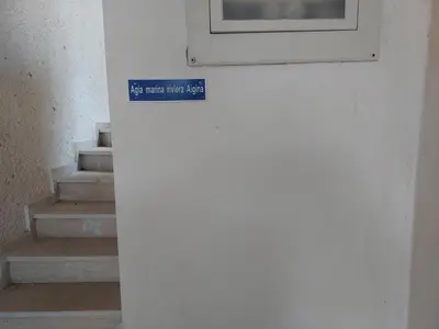 a blue sign on a wall next to some stairs at agia marina riviera aigina in Agia Marina Aegina