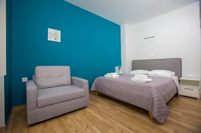 a bed and a chair in a room with blue walls at Athens Raise Acropolis Project in Athens