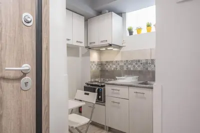 a small kitchen with white cabinets and a table at Welcoming Koukaki Home by Cloudkeys in Athens