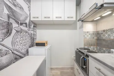 a kitchen with white cabinets and a drawing on the wall at Welcoming Koukaki Home by Cloudkeys in Athens