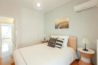 a white bedroom with a large white bed with pillows at Freshly Refurbished flat, in Central Koukaki in Athens