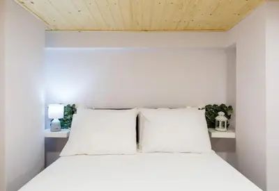 a white bed with white pillows in a room at Heart of Athens Studio 25sqm in Athens