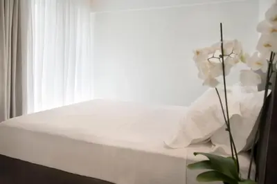 a bed with white sheets and a window at Glyfada South42 in Athens