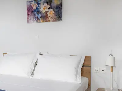 a bedroom with a white bed with a painting on the wall at Yellow house in Palaiá Fókaia